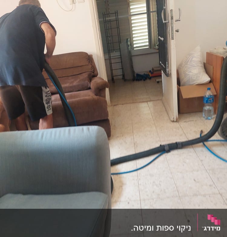 אדם מנקה ספה עם שואב אבק תעשייתי